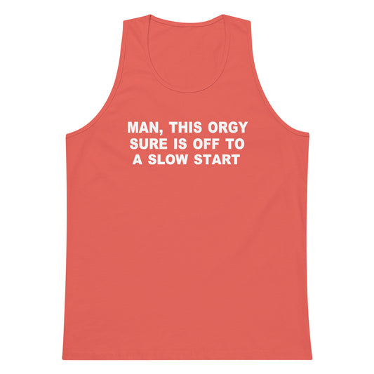 A coral red tank top with white text on the chest that reads 'MAN, THIS ORGY SURE IS OFF TO A SLOW START', shown against a plain white background.