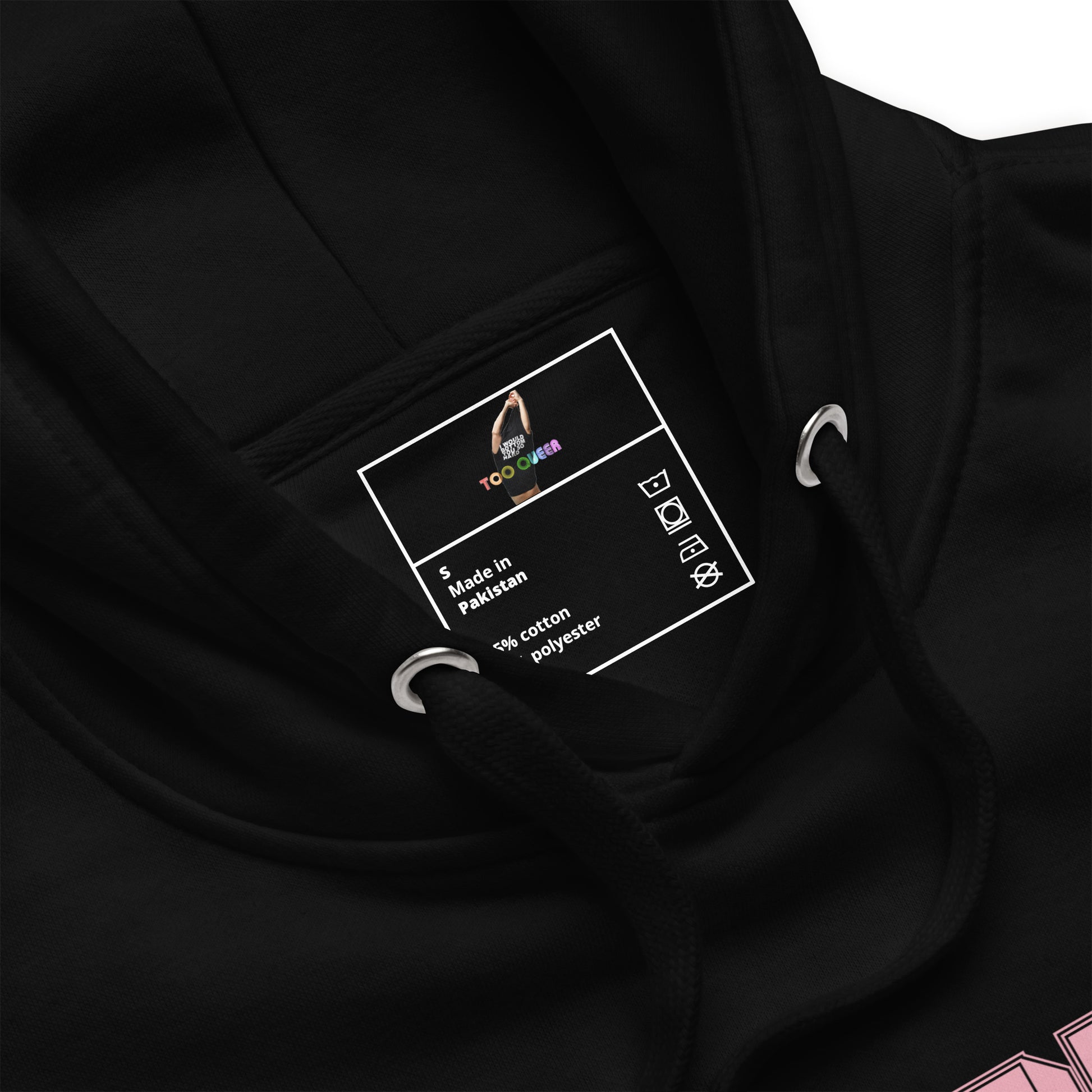 Close-up of a black hoodie showing the inner neck label with 'TooLoud' branding and 'Made in Pakistan' text, along with metal drawstring rings.