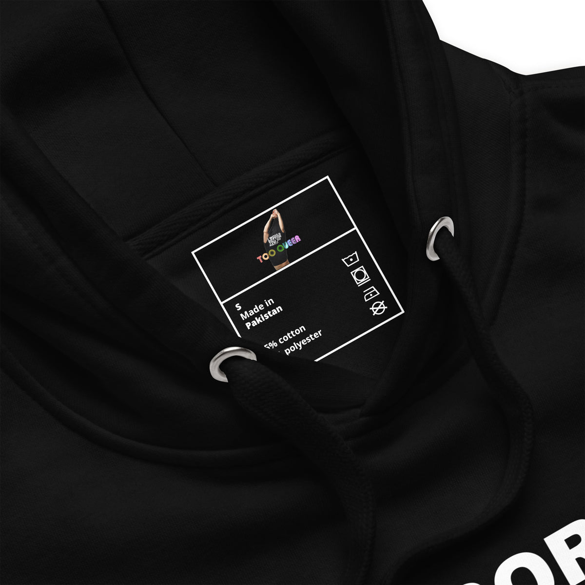 Close-up of a black hoodie interior neck label reading TOO LATE and Made in Pakistan, with drawstring rings and hood lining visible.