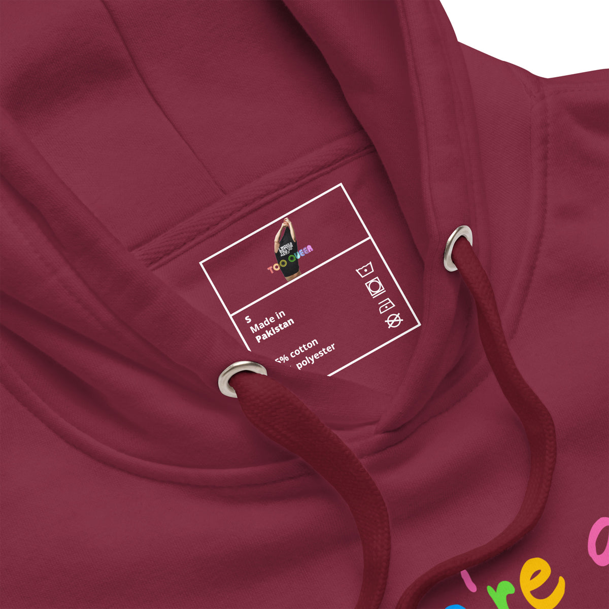 Close-up of a maroon hooded sweatshirt showing the inner pocket with a white printed care label and colorful drawstrings.