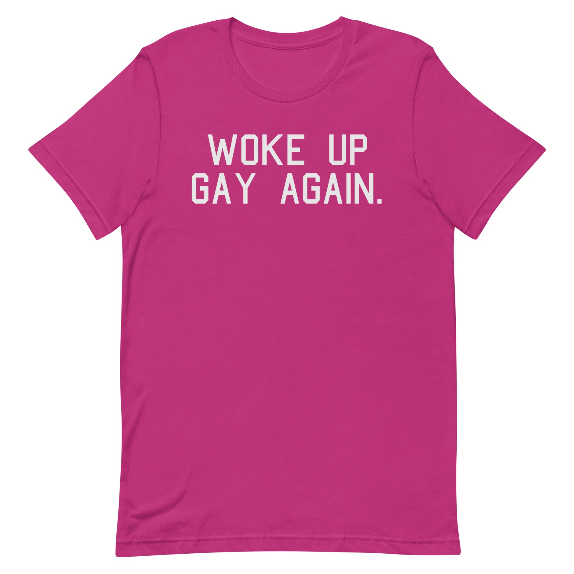 A bright pink short-sleeve t-shirt with the phrase 'WOKE UP GAY AGAIN.' printed in white block letters across the chest, displayed on a clean white background.