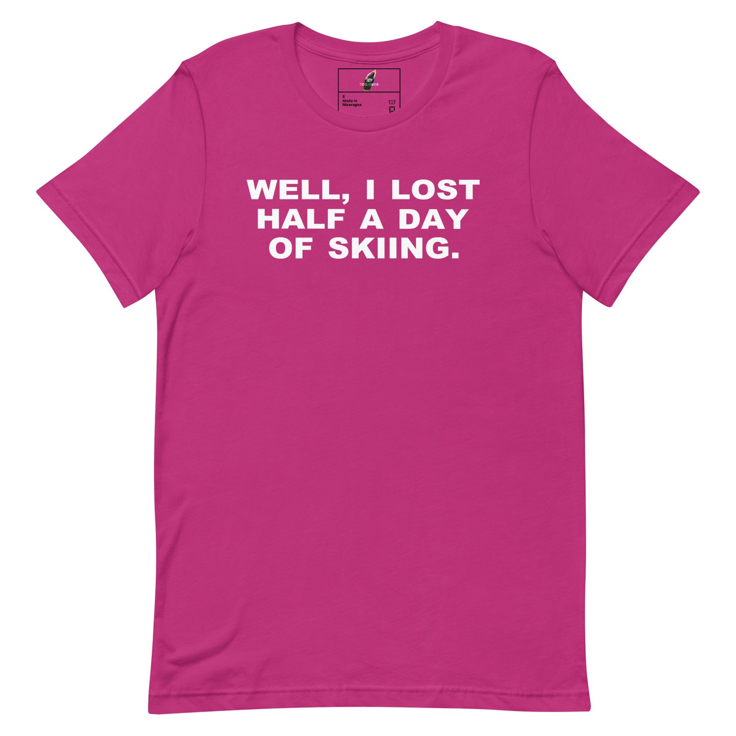 A bright pink short-sleeve crewneck t-shirt with the phrase 'WELL, I LOST HALF A DAY OF SKIING.' printed in bold white capital letters across the chest, displayed flat against a solid white background.