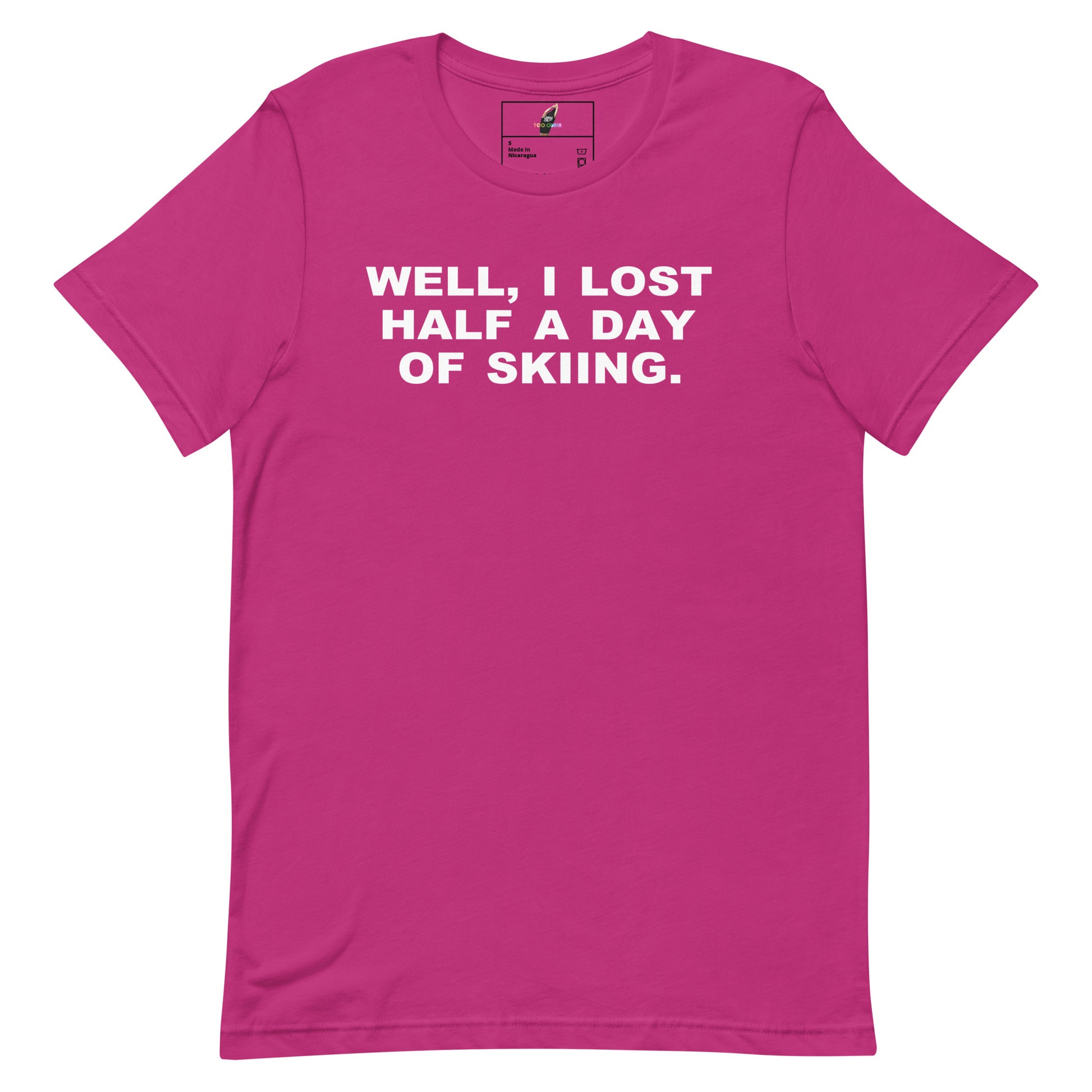 A bright pink short-sleeve crewneck t-shirt with the phrase 'WELL, I LOST HALF A DAY OF SKIING.' printed in bold white capital letters across the chest, displayed flat against a solid white background.