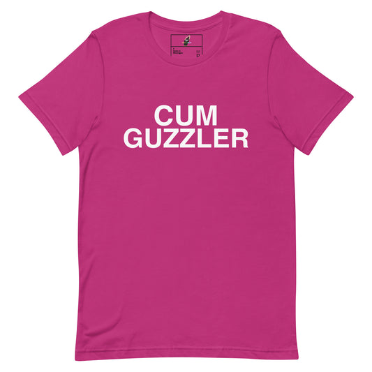 A bright pink short-sleeve crewneck t-shirt with the words 'CUM GUZZLER' printed in bold white capital letters across the chest, displayed on a solid white background.