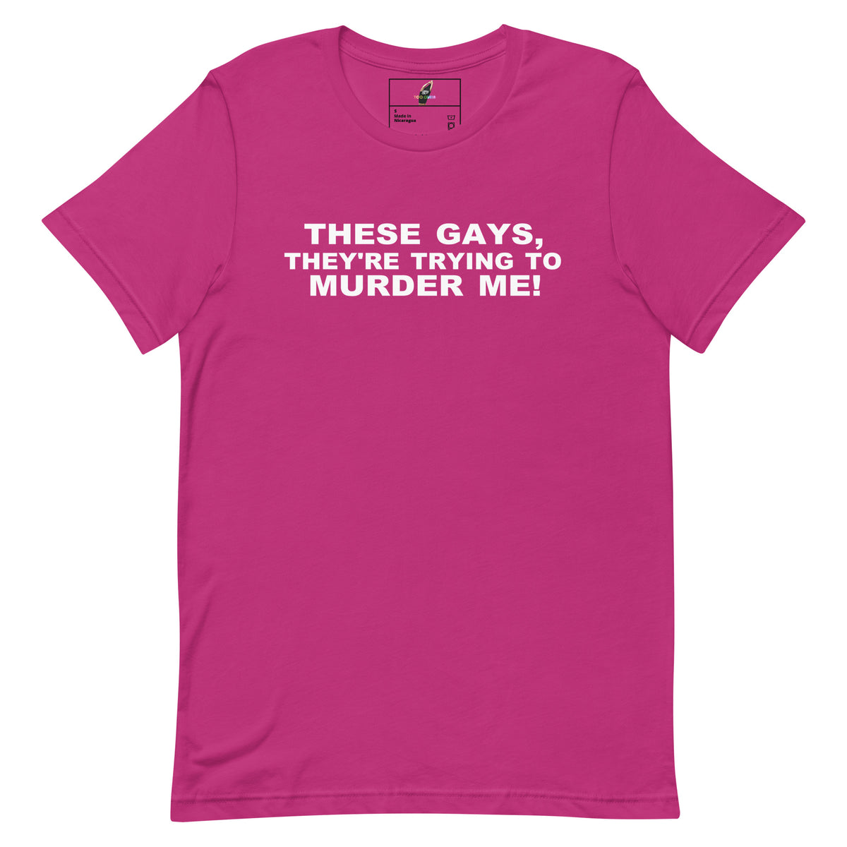 A bright pink short-sleeve crewneck t-shirt with bold white text on the chest reading 'THESE GAYS, THEY'RE TRYING TO MURDER ME!'. The shirt is displayed flat against a solid white background.