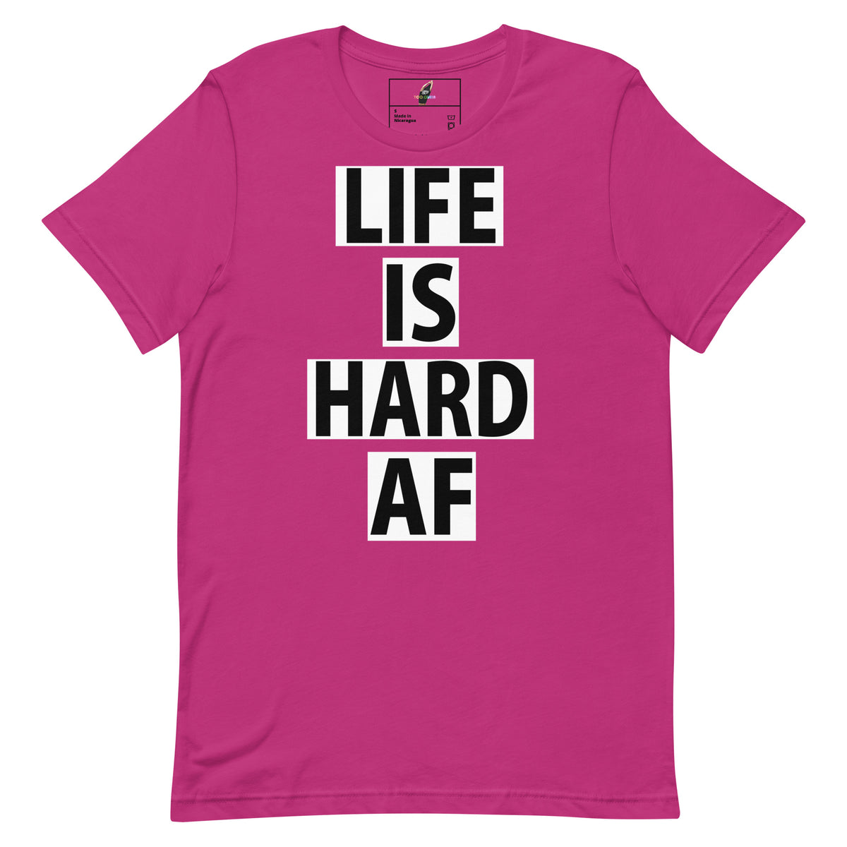 A bright pink short-sleeve t-shirt with the text 'LIFE IS HARD AF' printed in black block letters inside white rectangular blocks on the front.