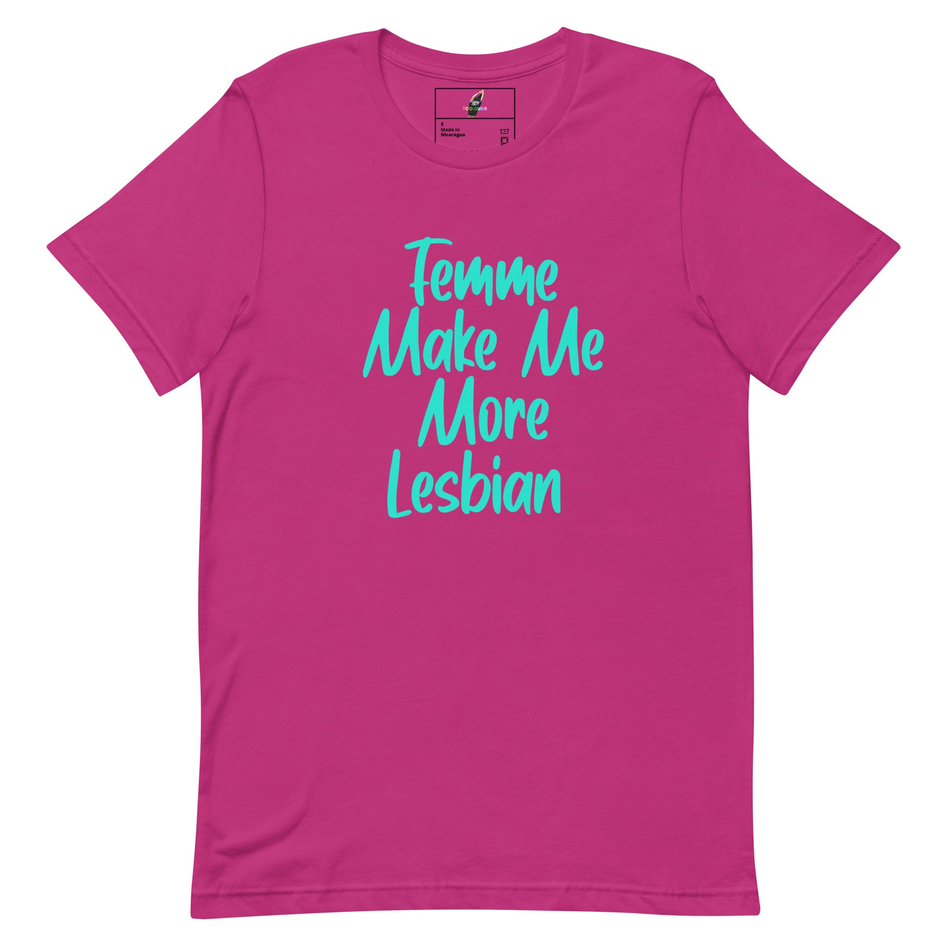 A bright pink short-sleeve t-shirt with the phrase 'Femme Make Me More Lesbian' printed in a light blue cursive font across the chest, displayed on a clean white background.