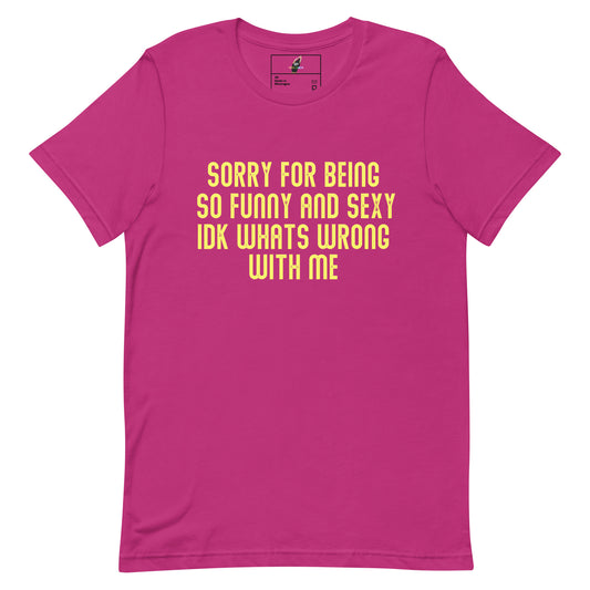 A bright pink short-sleeve t-shirt with yellow text on the front that reads 'SORRY FOR BEING SO FUNNY AND SEXY IDK WHATS WRONG WITH ME'.