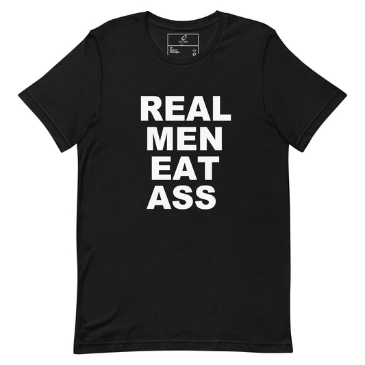 A black short-sleeve crewneck t-shirt with the phrase 'REAL MEN EAT ASS' printed in bold white capital letters on the front, displayed against a solid white background.