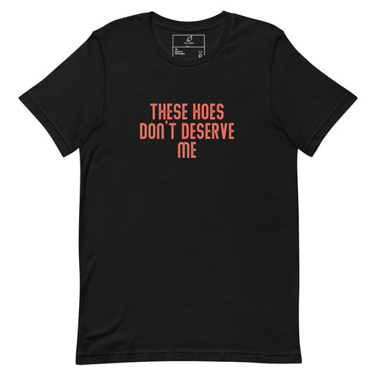 A black short-sleeve crewneck t-shirt with the text 'THESE HOES DON'T DESERVE ME' printed in orange across the chest, displayed on a solid white background.
