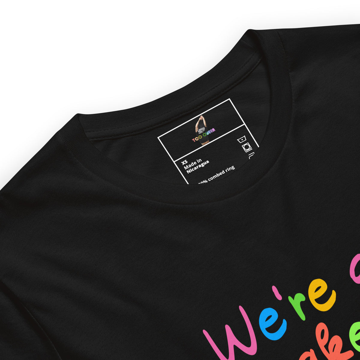 Close-up of a black short-sleeve t-shirt showing the inner neck label and part of a colorful graphic print on the lower right that reads 'We're a.