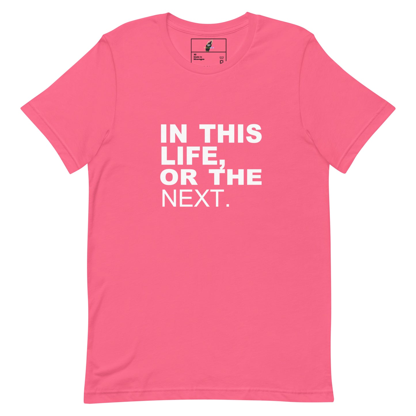 A pink short-sleeve crewneck t-shirt with the phrase 'IN THIS LIFE, OR THE NEXT.' printed in bold white capital letters on the front, displayed on a clean white background.