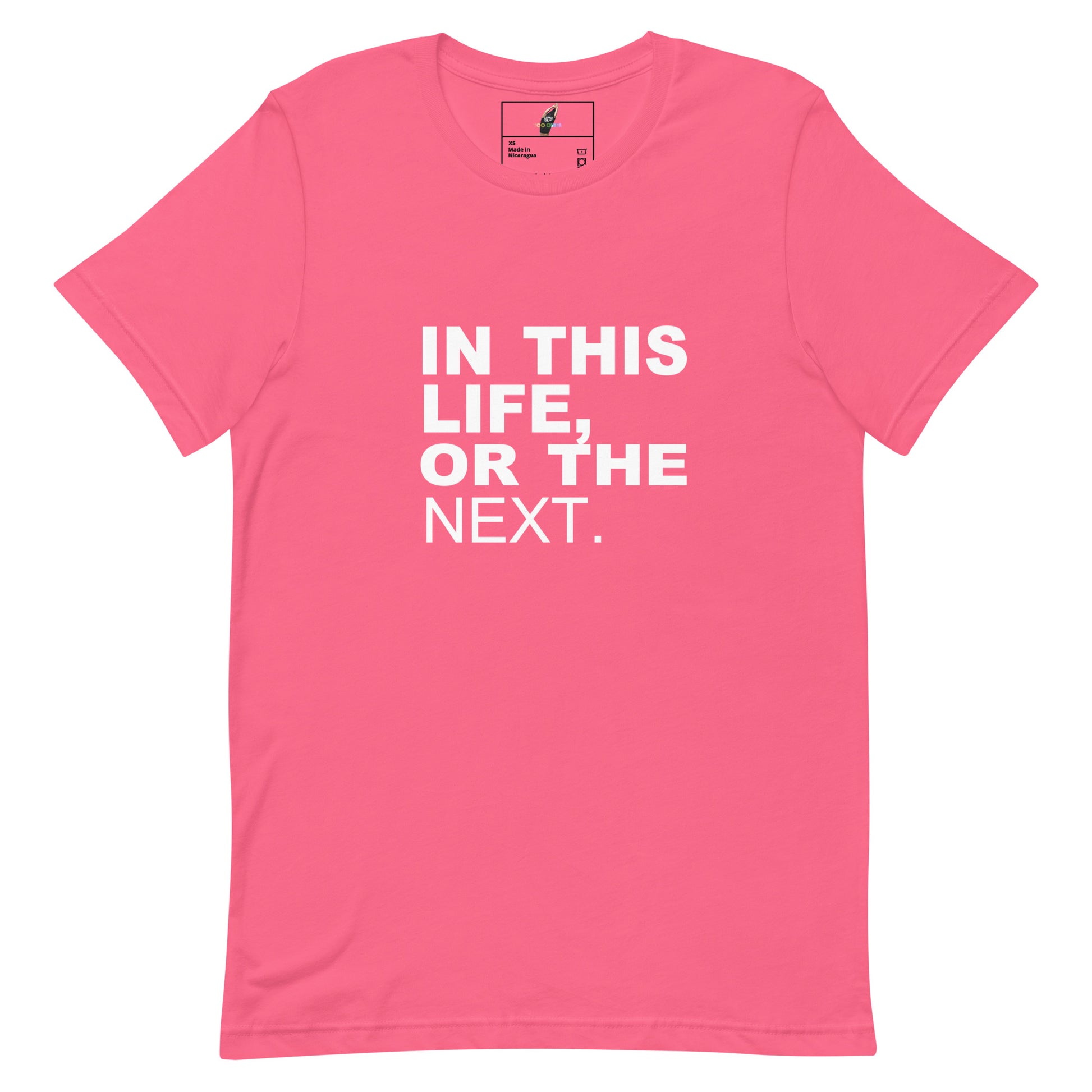 A pink short-sleeve crewneck t-shirt with the phrase 'IN THIS LIFE, OR THE NEXT.' printed in bold white capital letters on the front, displayed on a clean white background.