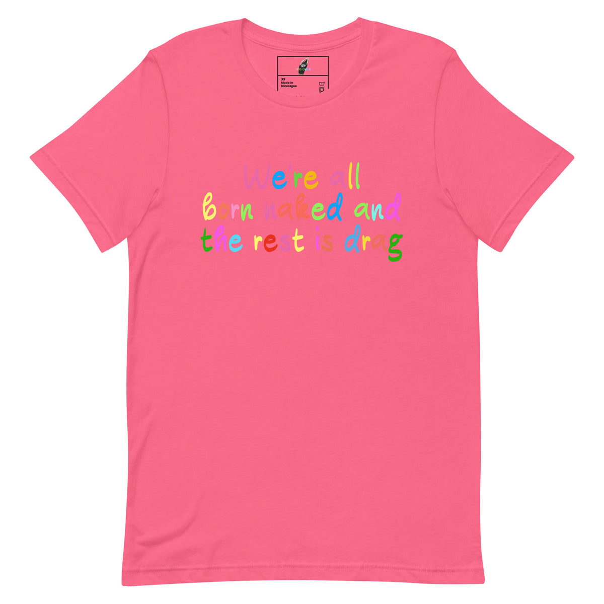 A pink short-sleeve crewneck t-shirt with a colorful text graphic on the chest reading 'we are all born made and the rest is drag' in various bright colors, shown against a plain white background.