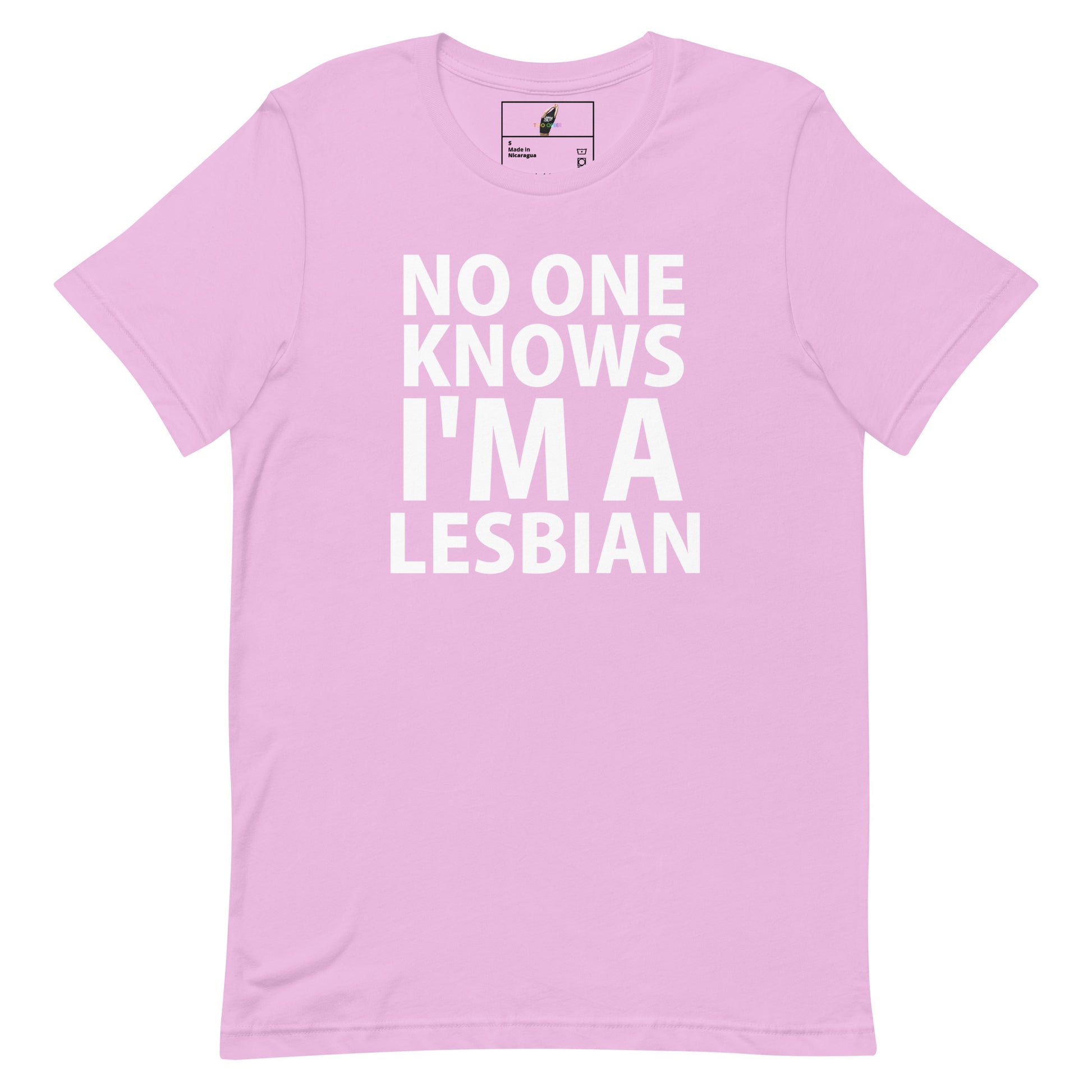 A light pink short-sleeve crewneck t-shirt with bold white text on the front reading 'NO ONE KNOWS I'M A LESBIAN'. The shirt is displayed flat against a solid white background, with a small brand label visible inside the collar.