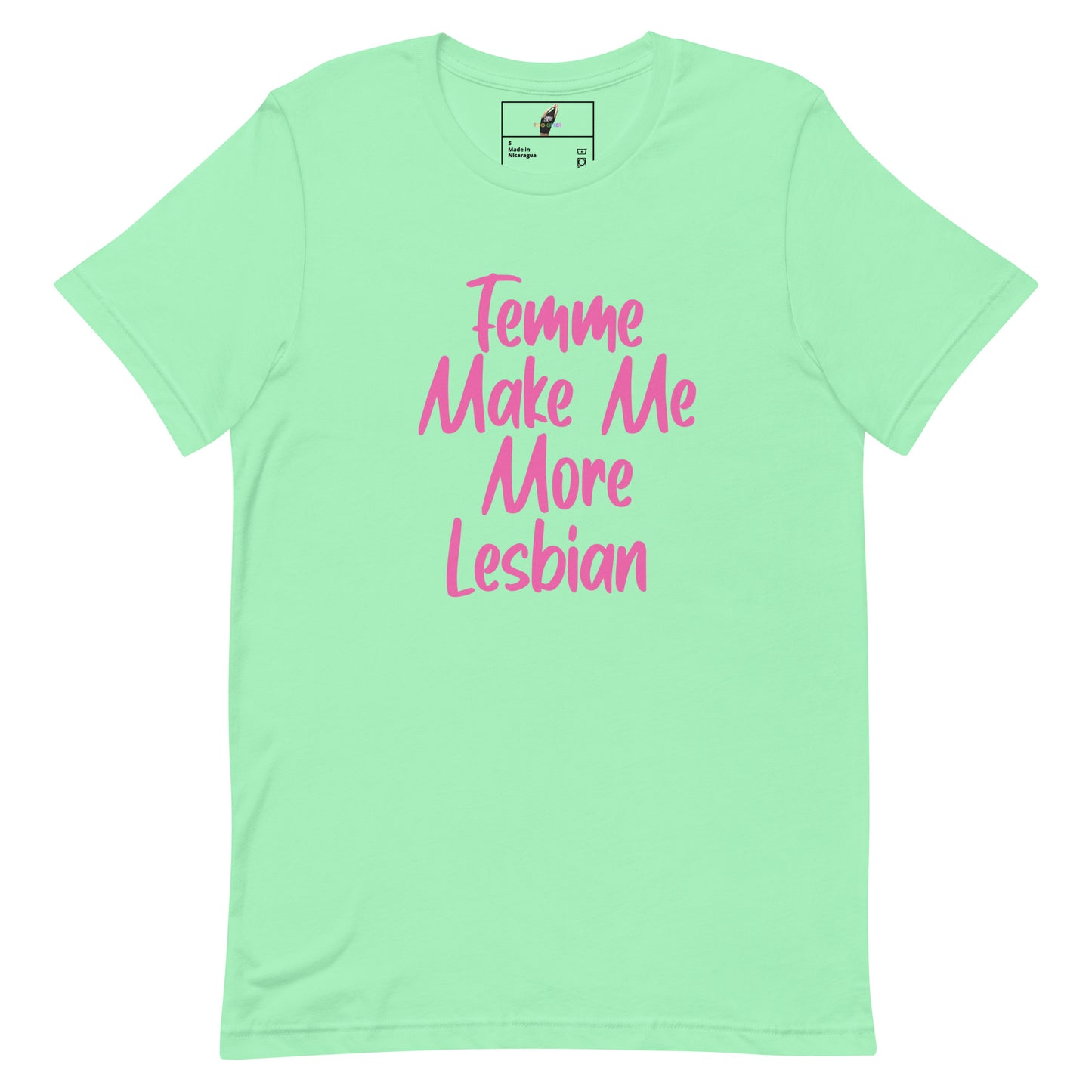 A mint green short-sleeve t-shirt with pink text on the front reading 'Femme Make Me More Lesbian'. The shirt is displayed flat against a solid white background, with a small brand label visible inside the collar.