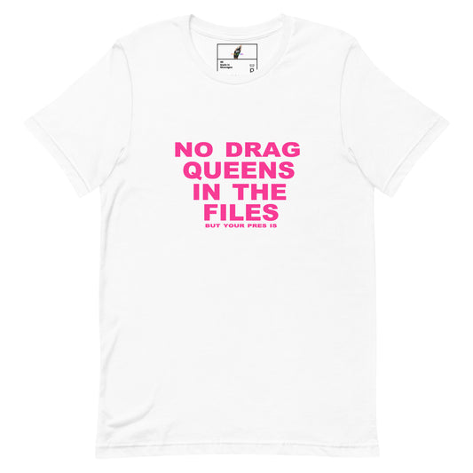 A white short-sleeve crewneck t-shirt with bold pink text on the front reading 'NO DRAG QUEENS IN THE FILES' and smaller text below reading 'BUT YOUR FREE IS'. The shirt is displayed flat against a clean white background.