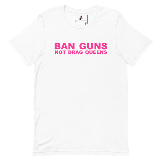 A white short-sleeve crewneck t-shirt with the slogan 'BAN GUNS NOT DRAG QUEENS' printed in bright pink across the chest.
